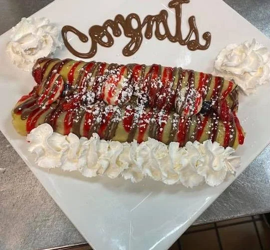 A crepe decorated with “Congrats” in chocolate and whipped cream