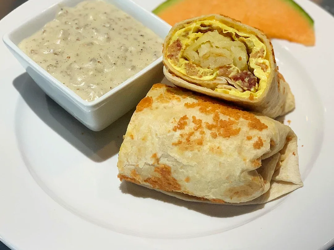Breakfast burrito with a side of sausage gravy and melon